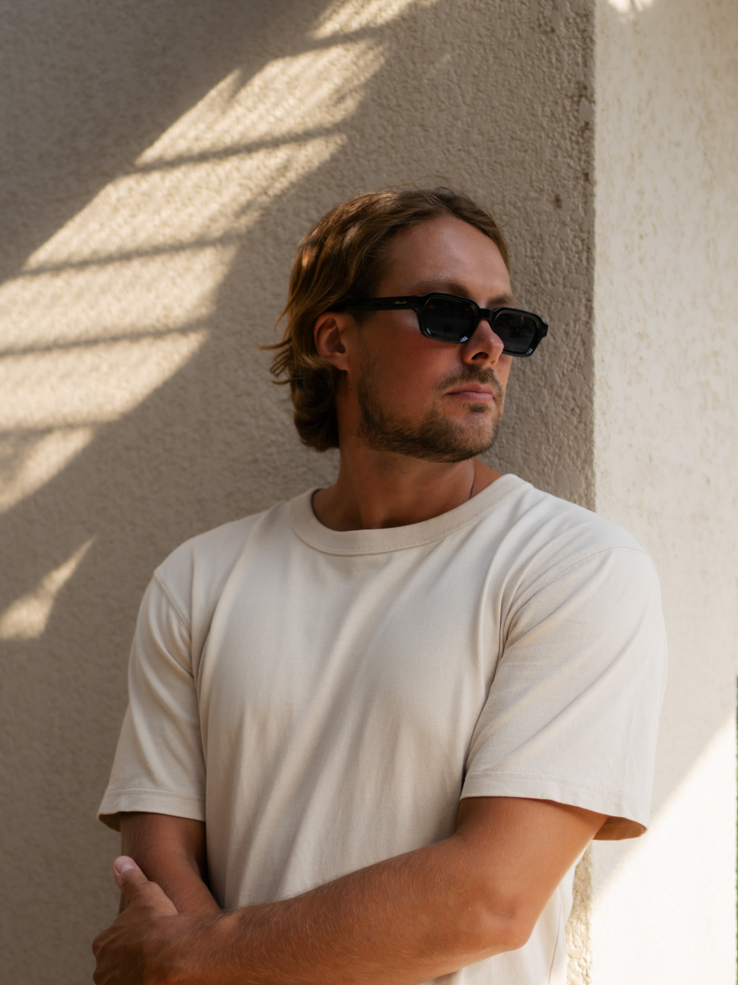 Lifestyle portrait of Teemu in sunglasses beside a sunlit wall