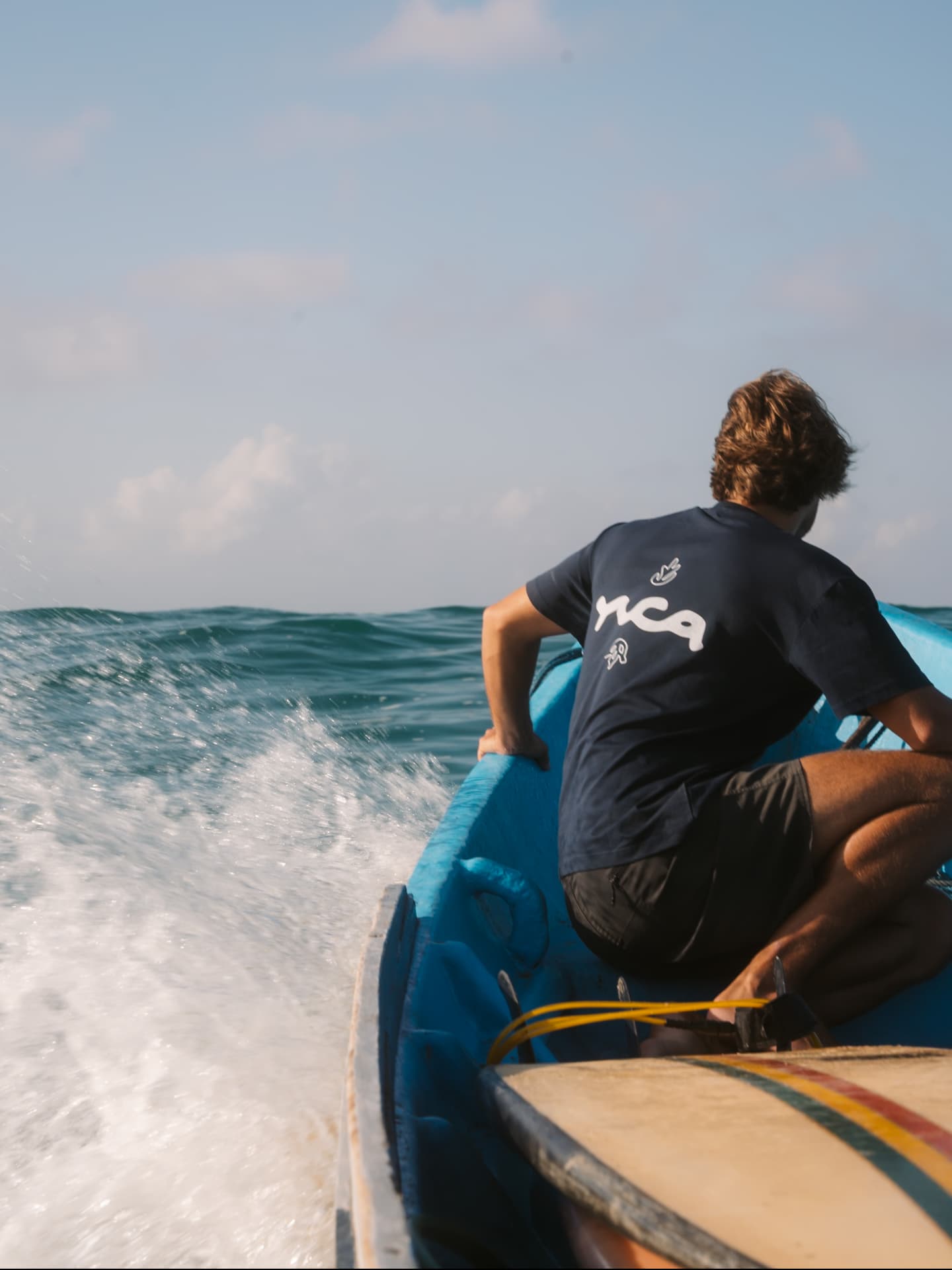 Surfer looking out at waves from a traditional boat